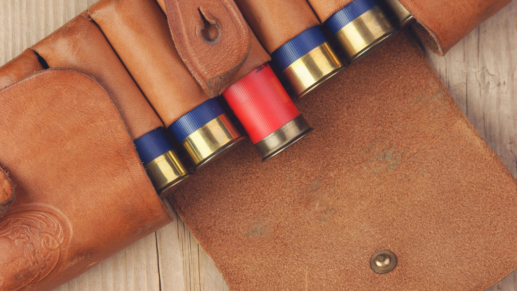 Old hunting cartridges and bandoleer on a wooden table